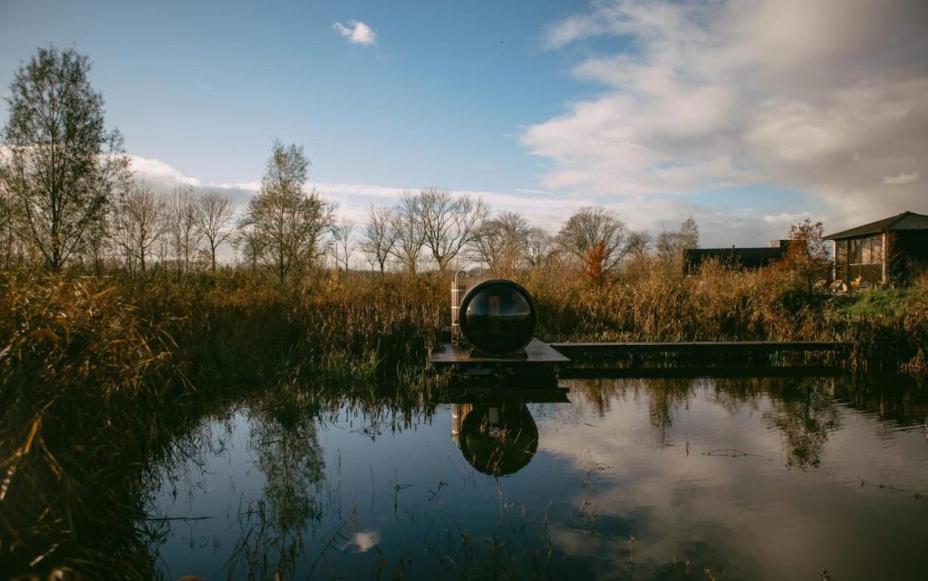 Paysage naturel avec un canal et une zone boisée sous un ciel nuageux