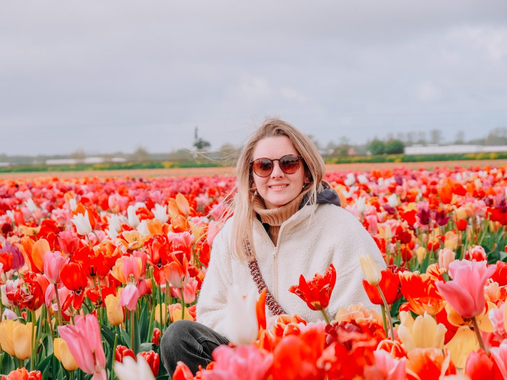 Eloïse posant dans un champ de tulipes multicolores, sourire aux lèvres