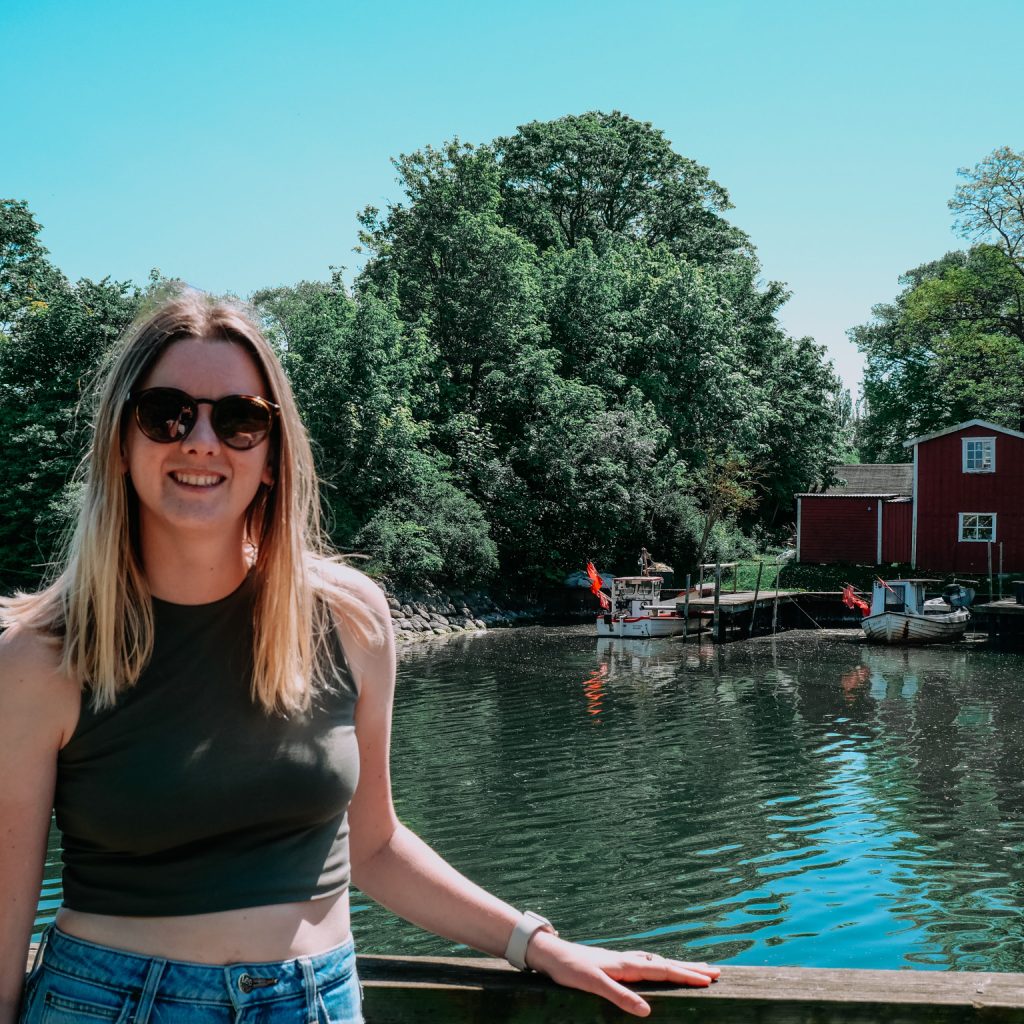 Eloïse assise près d'une rivière dans une ville, entourée de végétation.
