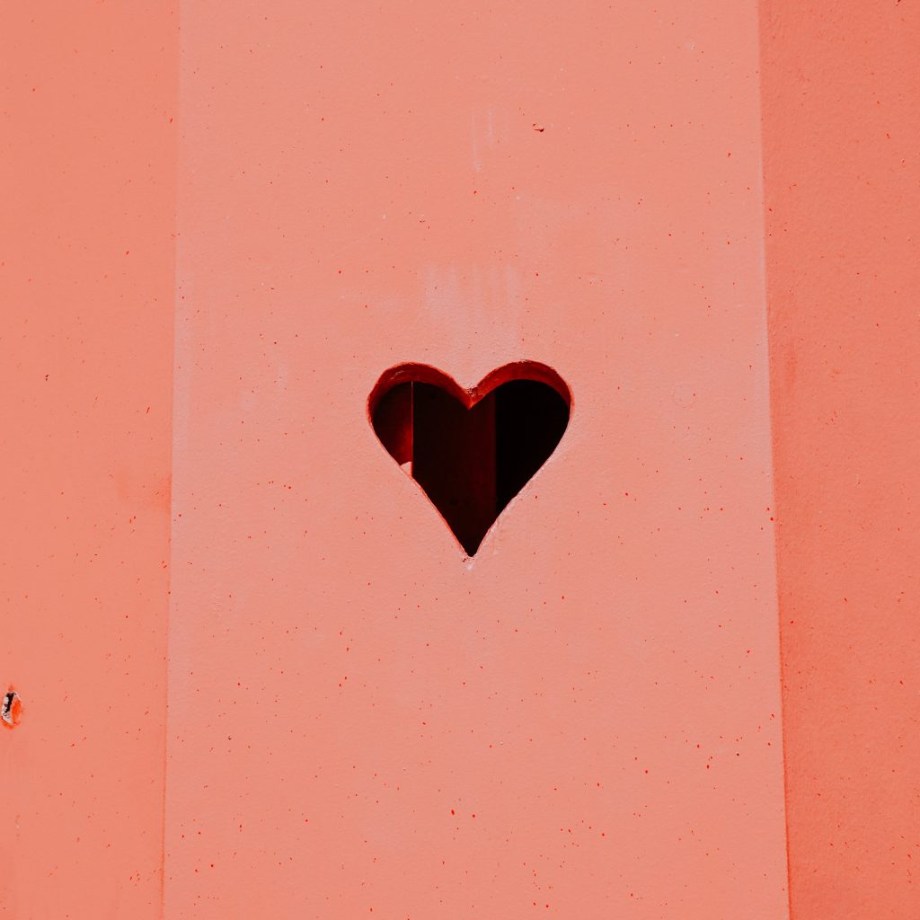 Mur orange avec un cœur découpé dans une plaque en métal.